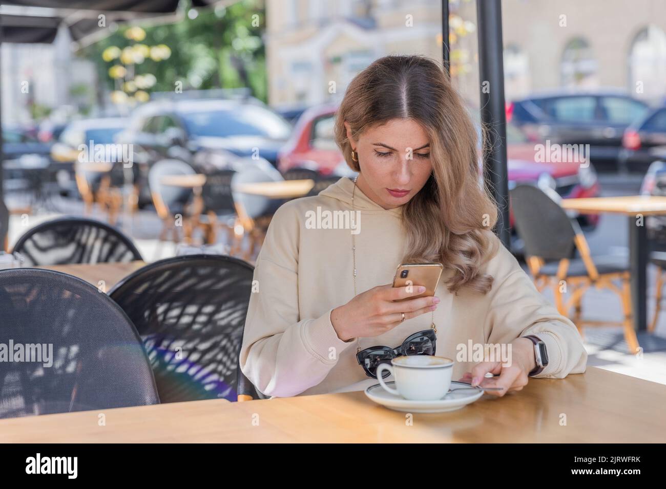 La ragazza fa foto sul telefono in caffè in terrazza. Foto Stock