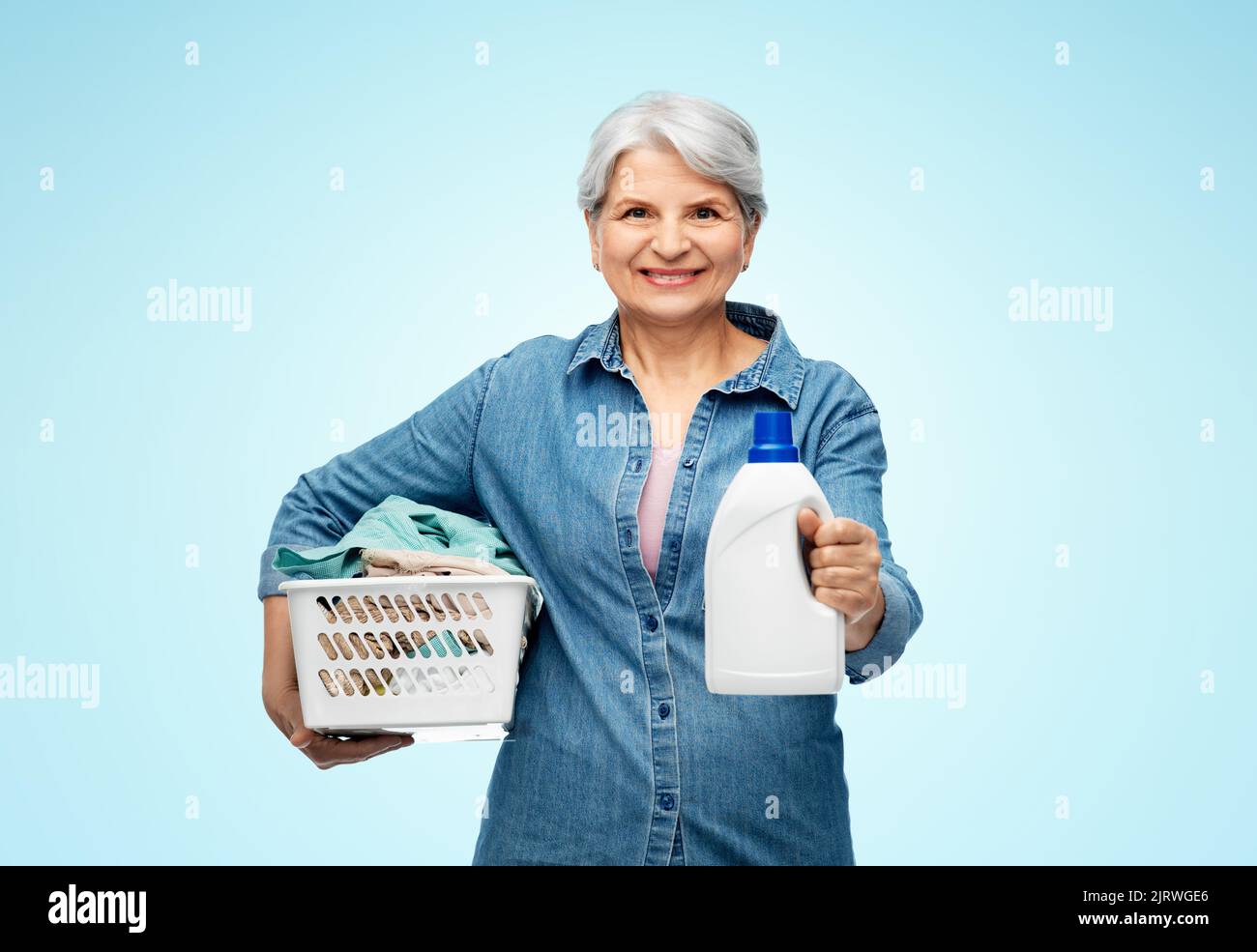 donna anziana sorridente con cesto per la lavanderia Foto Stock