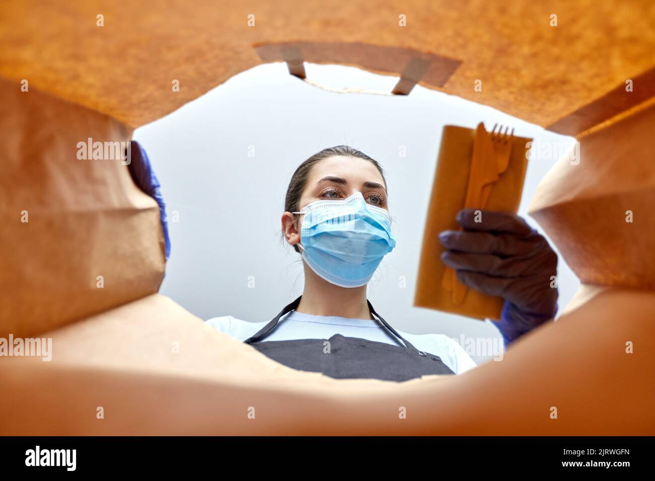 venditore in guanti e maschera imballaggio cibo in sacchetto Foto Stock