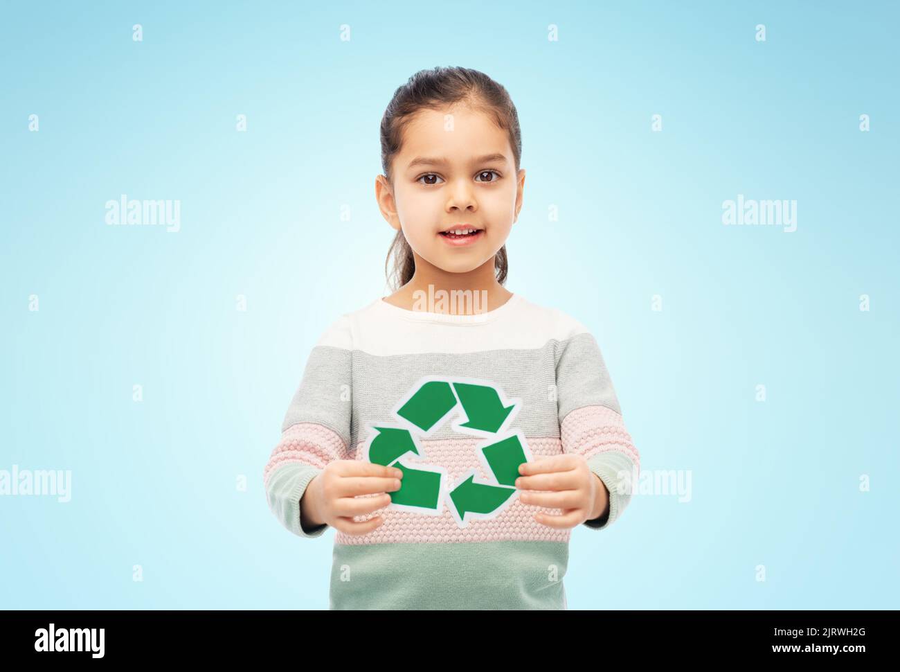 ragazza sorridente che tiene il segno verde di riciclaggio su blu Foto Stock