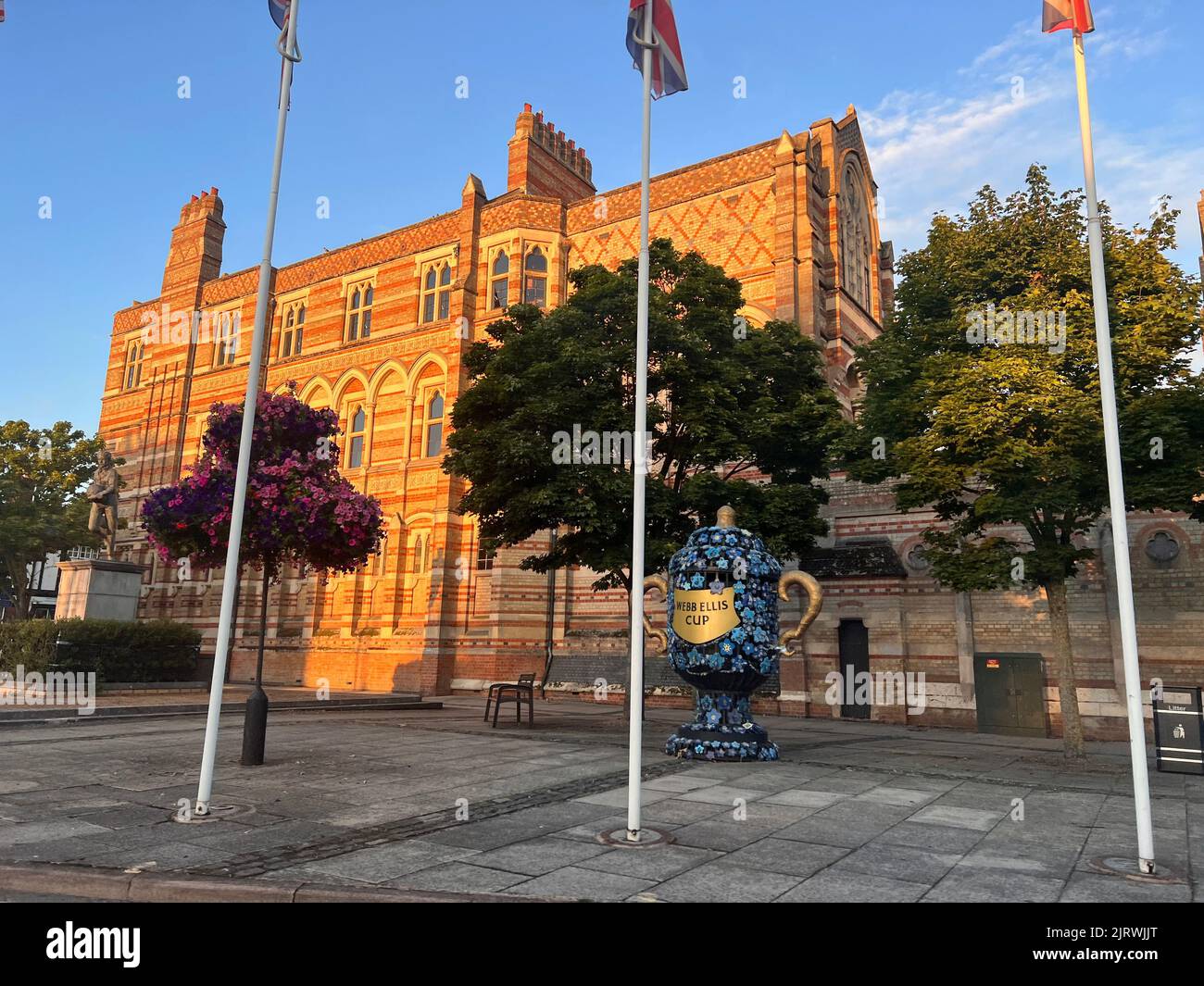 La facciata del Museo di Rugby durante il giorno con i pali della bandiera davanti ad esso e una decorazione fatta di rose Foto Stock