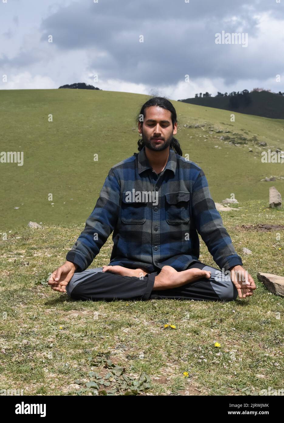 Vista frontale di un giovane indiano che pratica yoga in posa Lotus (Padmasana) con Gyan Mudra (Gesture of Knowledge) in montagna. Foto Stock
