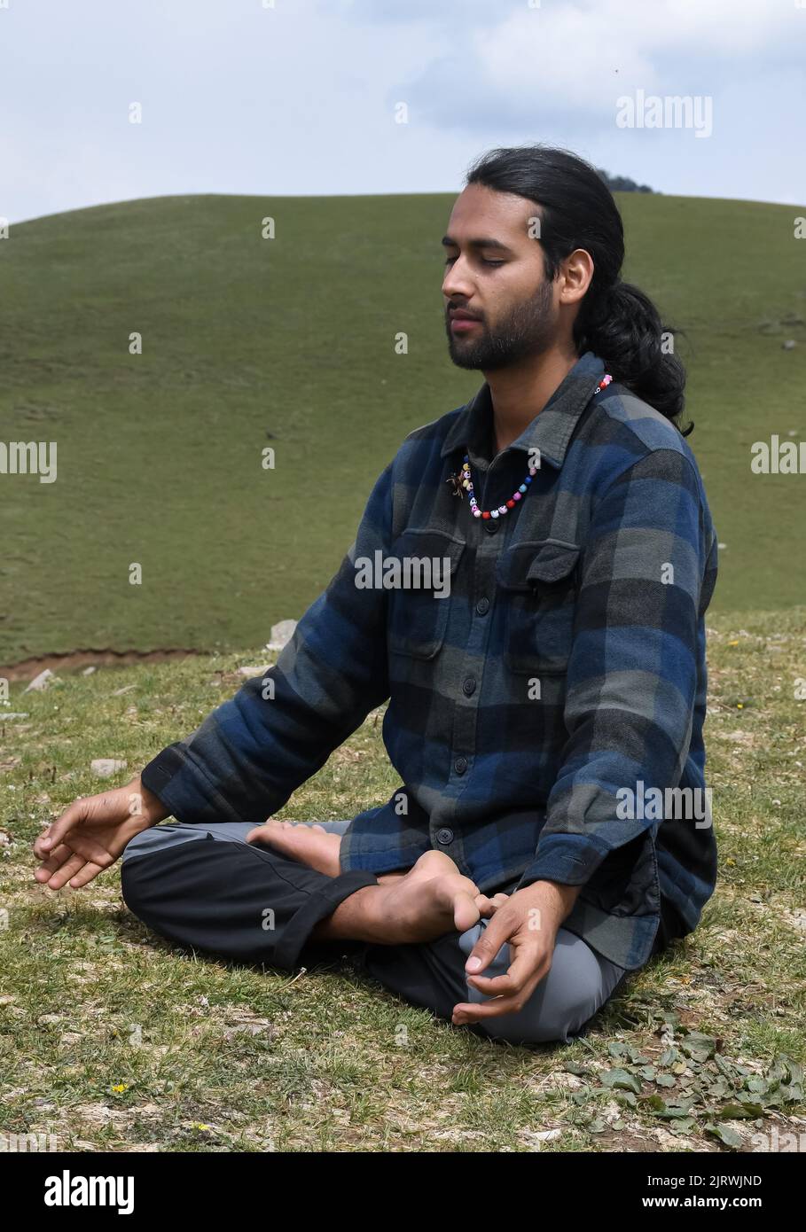 Un giovane indiano che pratica Yoga in posa del loto (Padmasana) con Gyan Mudra (Gesture of Knowledge) in montagna. Foto Stock