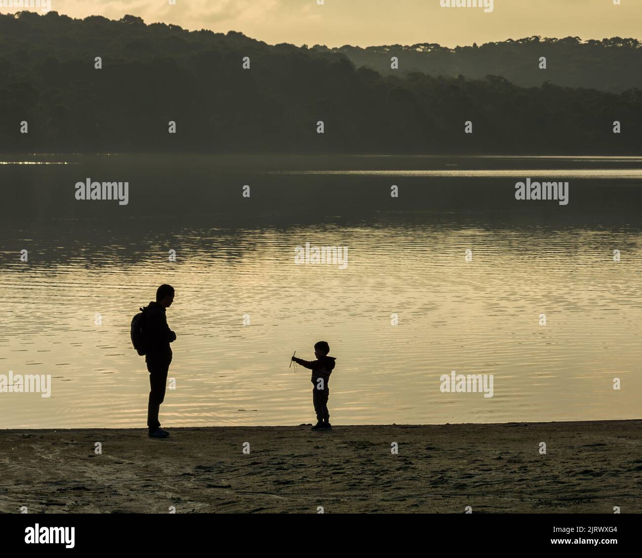 Padre e figlio che legano il rapporto di famiglia al tramonto su un lago, silhouette foto simbolica Foto Stock