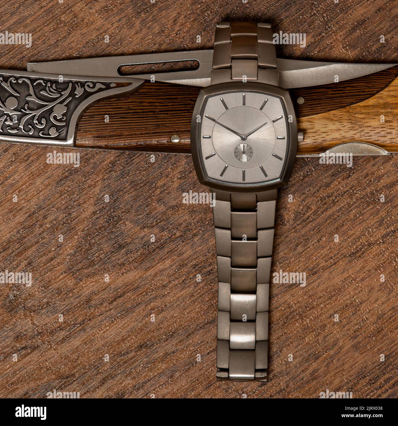 Orologio da polso in titanio su coltello ripiegabile a mano su foto stock di legno Foto Stock