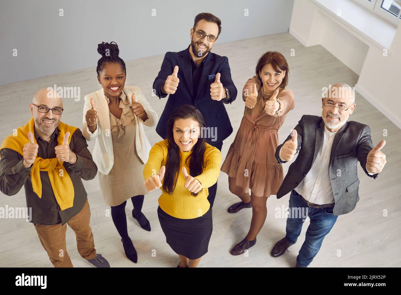 Un team diversificato di persone felici che sorridono e mostrano i pollici verso l'alto gesti insieme Foto Stock
