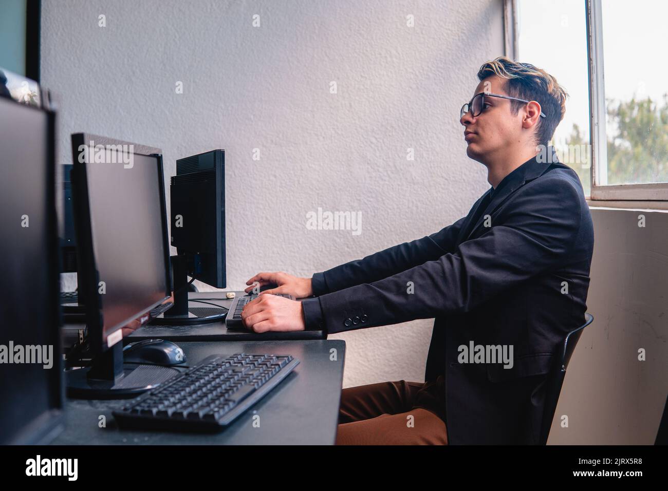 Lavoratore dell'ufficio che lavora al computer al suo lavoro. Uomo caucasico biondo elegantemente vestito nell'ufficio della sua compagnia. Foto di alta qualità Foto Stock