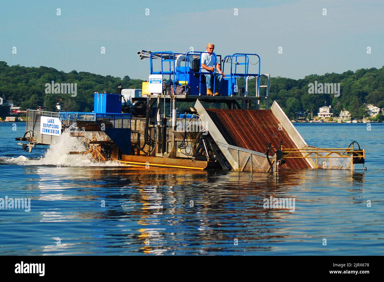 Un lavoratore gestisce una macchina dragante per rimuovere inquinanti, tossine e specie invasive dal fondo del lago Foto Stock