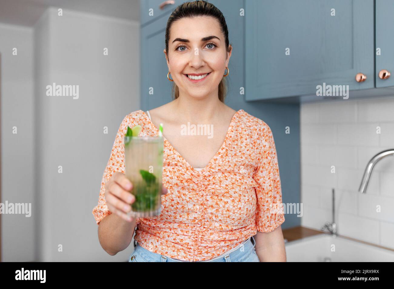donna con mojito lime cocktail in cucina a casa Foto Stock