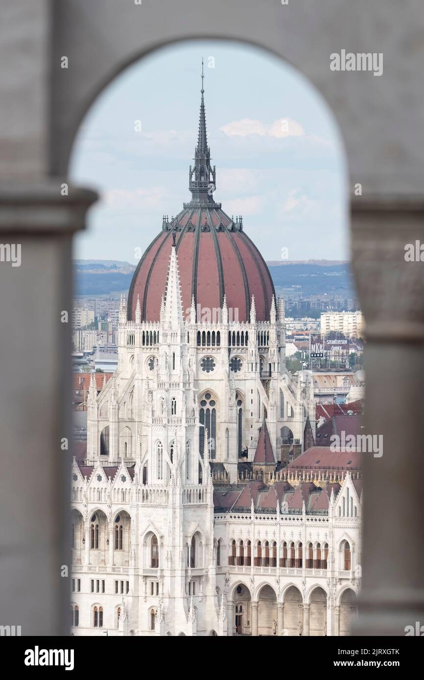 Vista incorniciata dall'arco dell'edificio del Parlamento ungherese a Budapest sul Danubio. Foto Stock