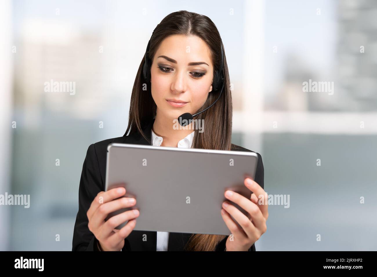 Donna che partecipa a una riunione remota utilizzando un tablet e. cuffia Foto Stock