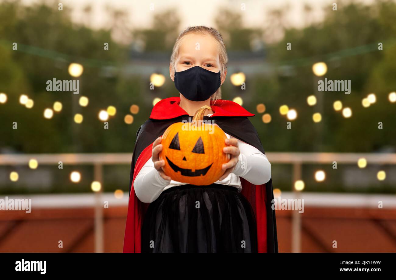 ragazza in costume di halloween e maschera con zucca Foto Stock