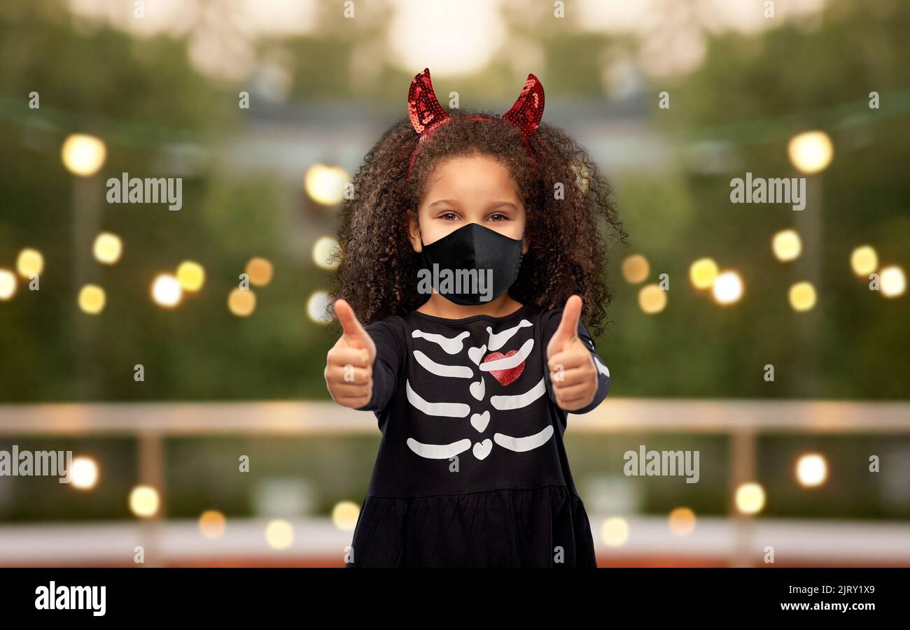 ragazza in maschera nera che mostra i pollici su su su halloween Foto Stock