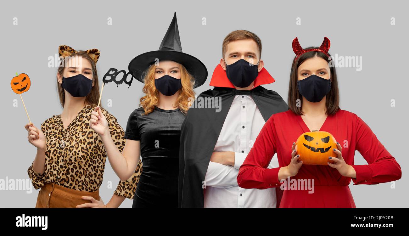 amici in costumi di halloween e maschere nere Foto Stock