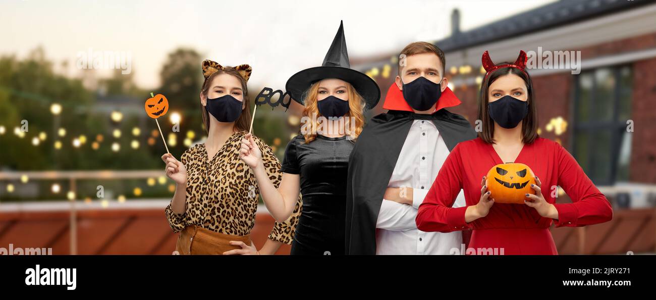 amici in costumi di halloween e maschere nere Foto Stock