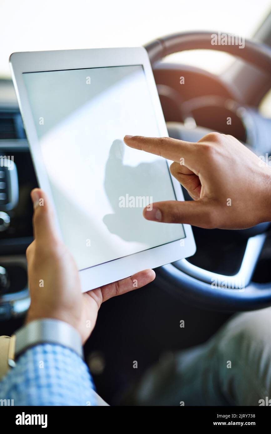 Lavoro svolto anche lontano dalla scrivania. Un uomo non identificabile che utilizza un tablet digitale mentre guida un'auto. Foto Stock