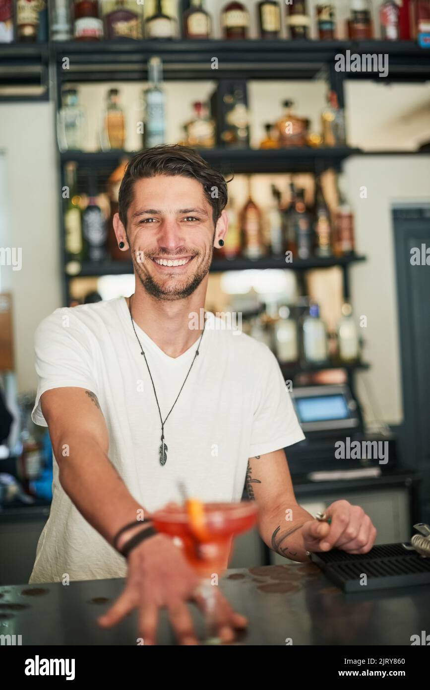 Hai servito. Ritratto di un giovane e felice barista che serve un cocktail dietro il bar. Foto Stock