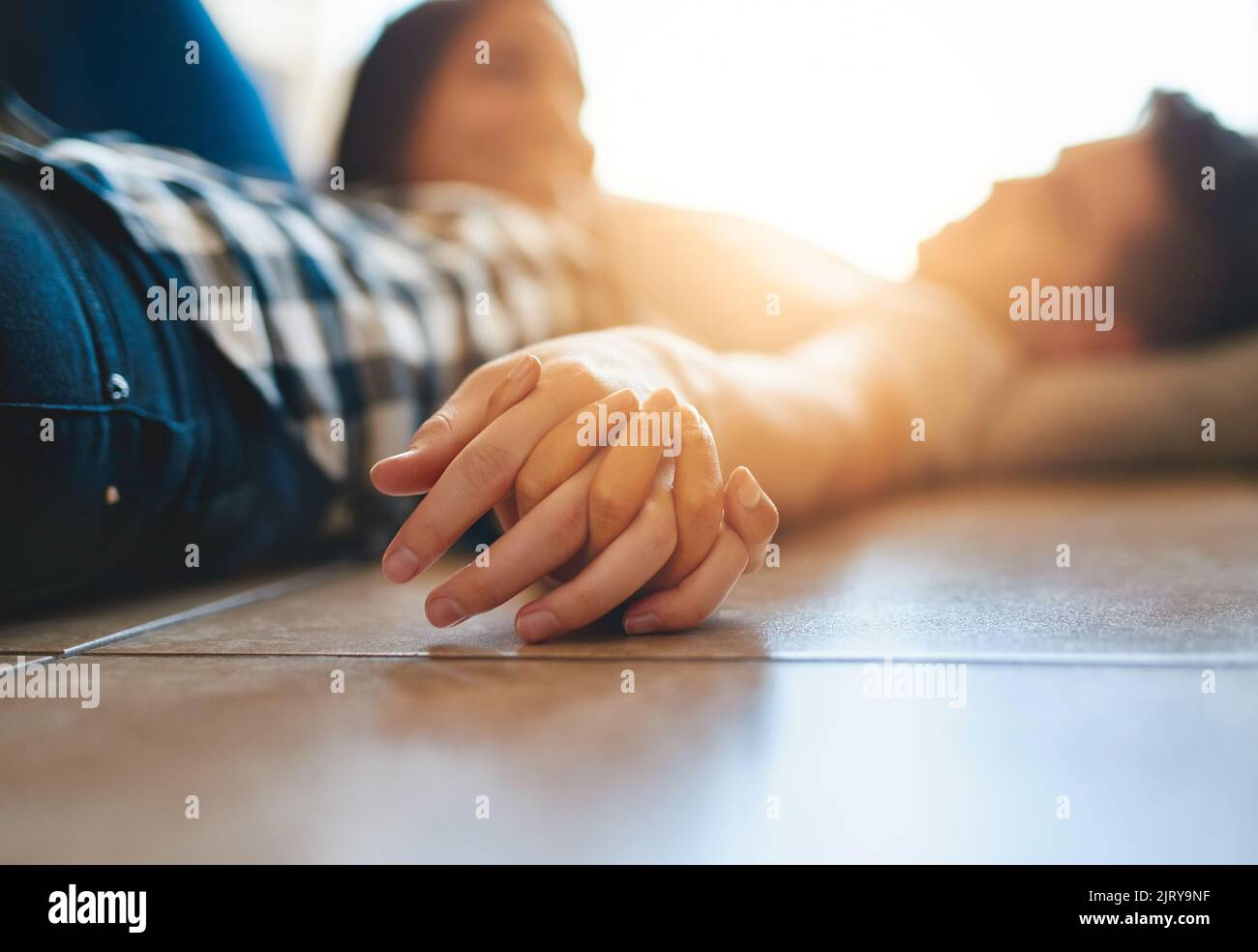 Andando nel futuro mano in mano. Una giovane coppia felice che riposa sul pavimento mentre si sposta nella loro nuova casa. Foto Stock