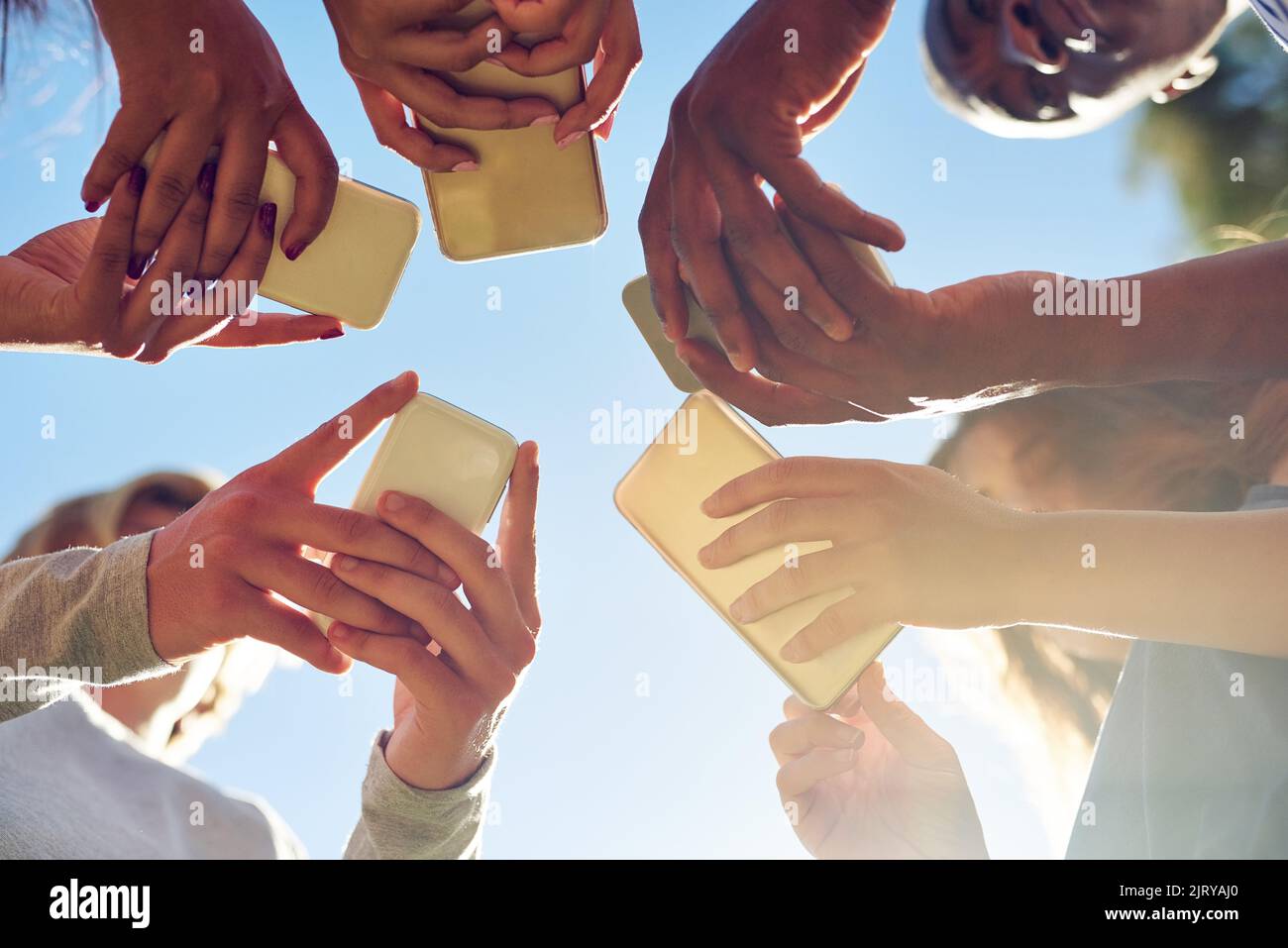 La generazione intelligente. Un gruppo di amici che usano il telefono insieme all'aperto. Foto Stock