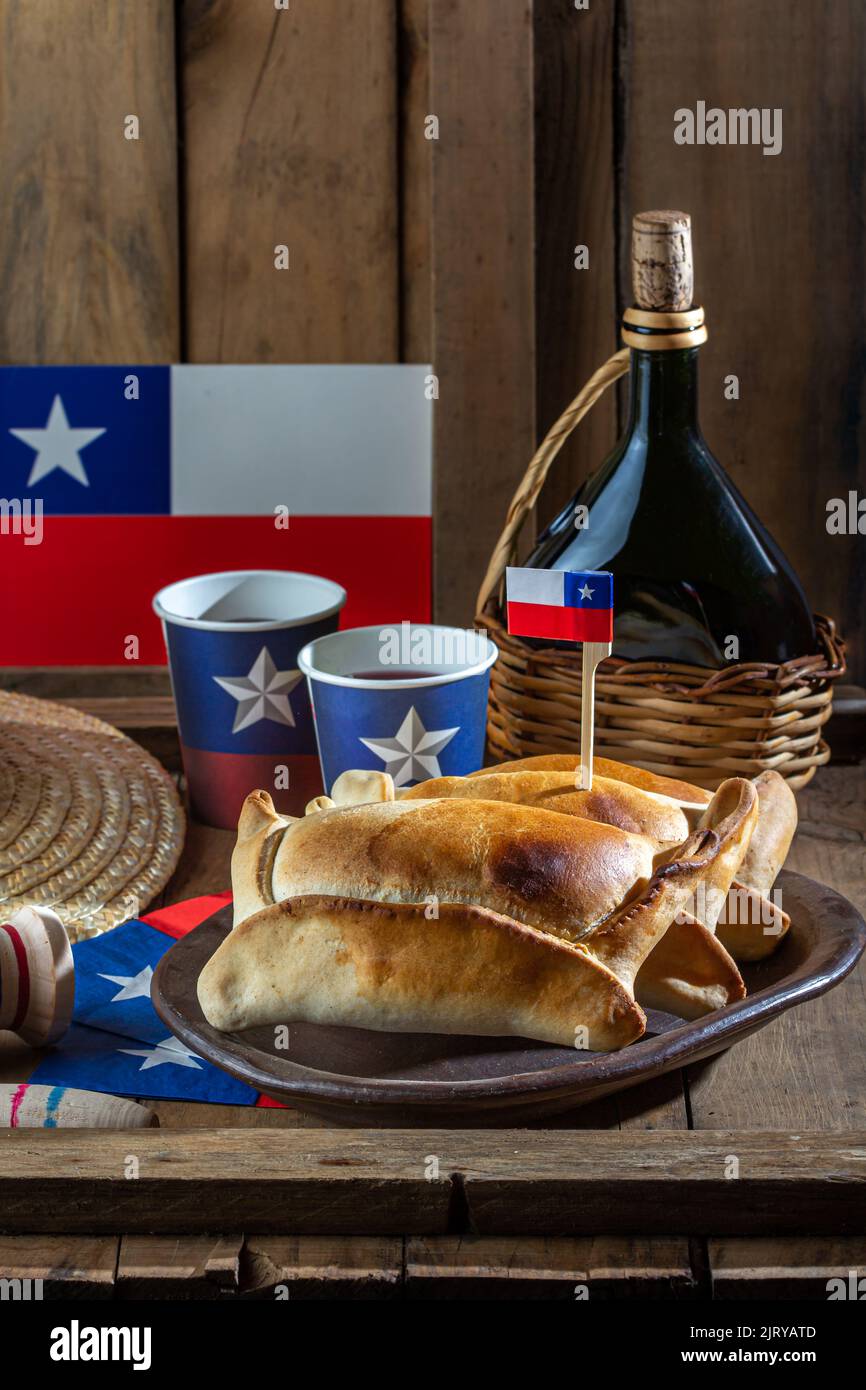 Concetto cileno giorno di indipendenza. Fiestas patrias. Empanadas de pino al forno, vino o chicha, cappello e gioco a emboque. Piatto e bevanda il 18 settembre Foto Stock