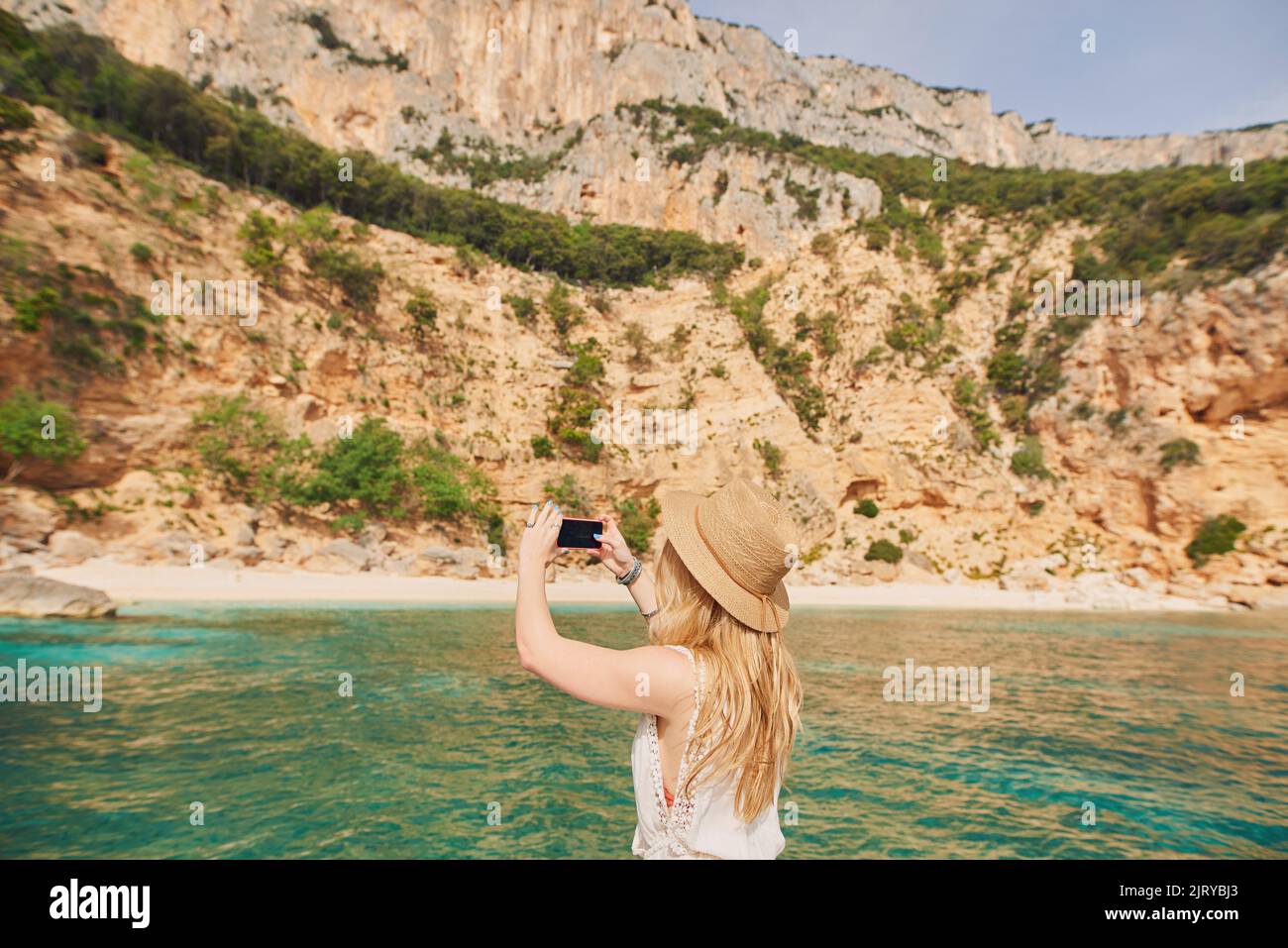 Bella donna in motoscafo guida verso la spiaggia paradiso isola prendere foto smartphone Scopri estate avventura vacanza Foto Stock