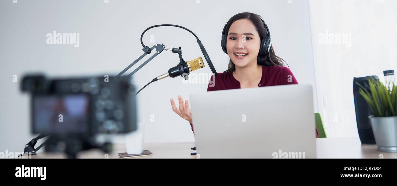 Giovane donna asiatica che registra e lavora come dj e podcast, trasmettendo il concetto di home studio Foto Stock