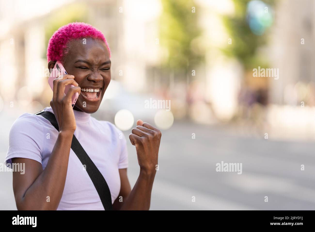 Giovane donna africana che ride mentre parla con i mobili all'aperto Foto Stock