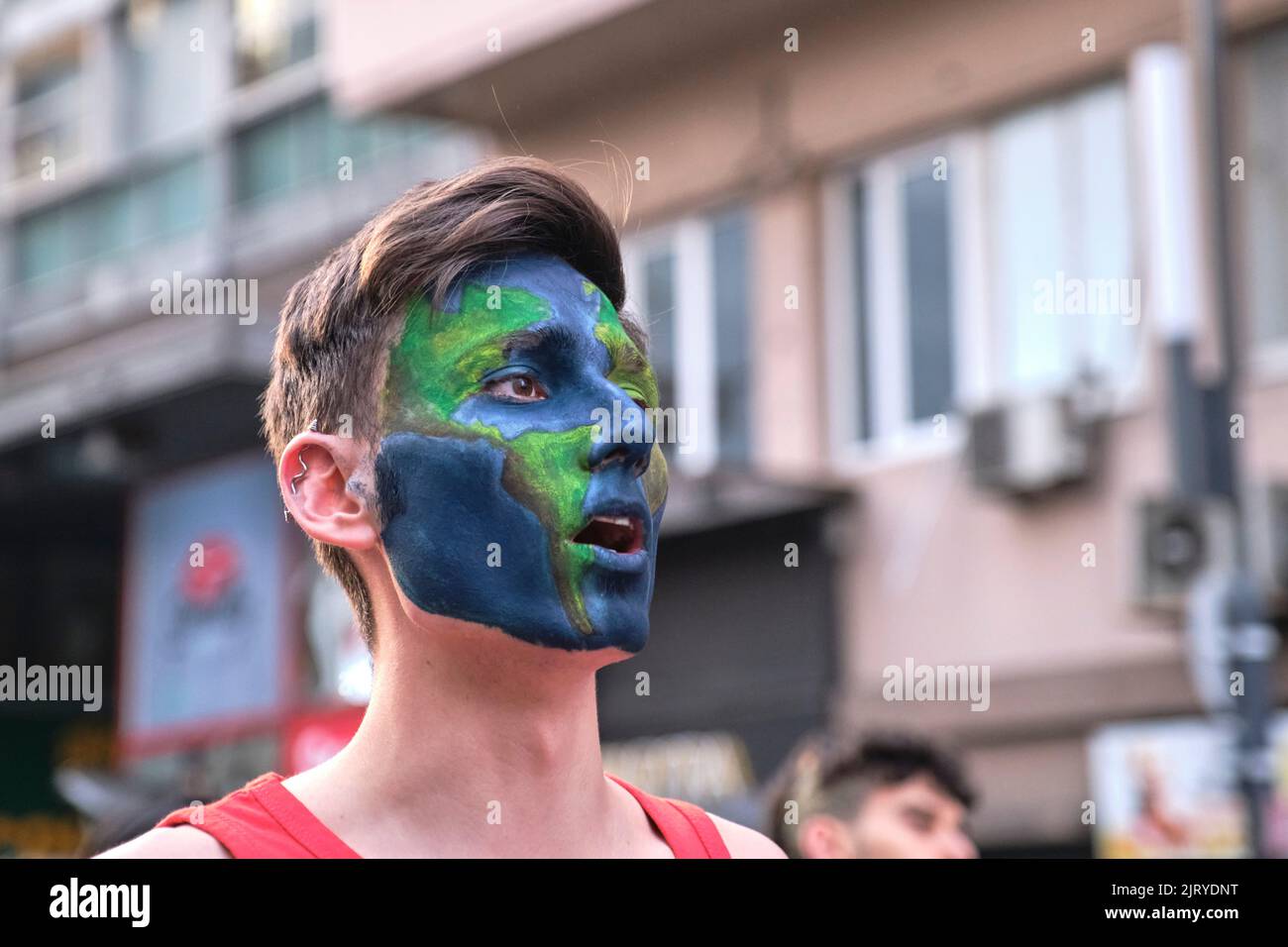 Buenos Aires, Argentina; 25 agosto 2022: Giovane uomo con terra del pianeta dipinto sul suo volto urlando ad una dimostrazione ambientale. Foto Stock