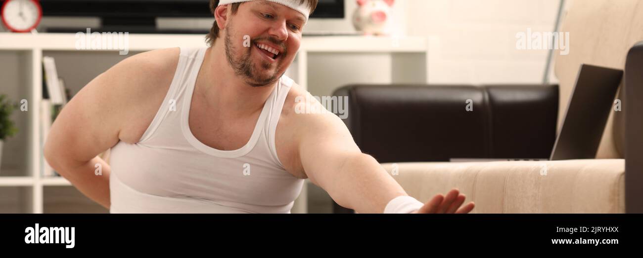 L'uomo di idoneità si trova su tappeto spesso con peso in eccesso, esegue esercizi di stretching Foto Stock