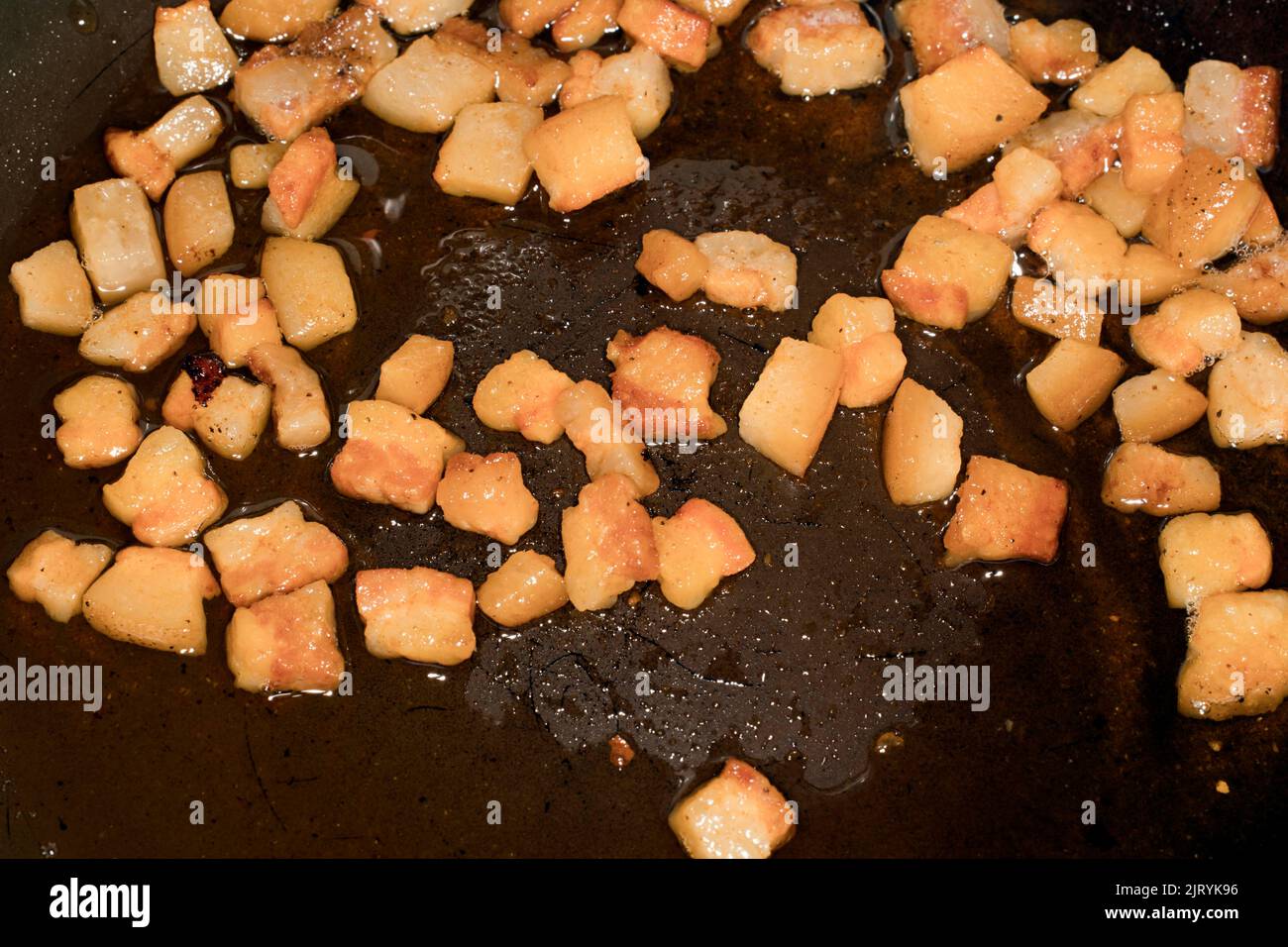 I cubetti di pancetta sono fritti in una padella, nella loro propria fotografia grassa del cibo Foto Stock
