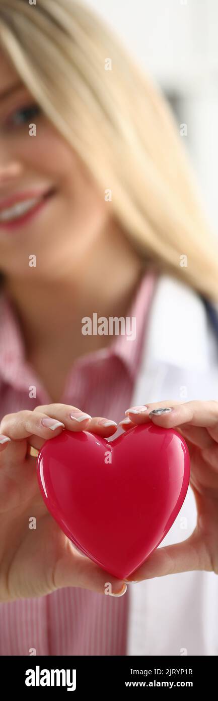 Il cardiologo tiene il cuore rosso nelle mani a primo piano Foto Stock