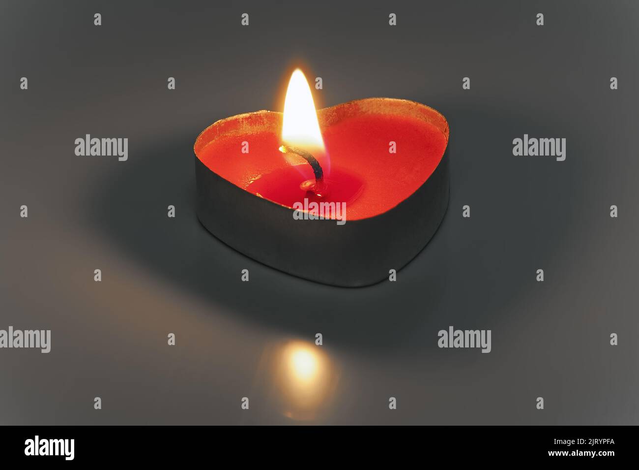 La piccola candela bruciante a forma di cuore isolato Foto Stock