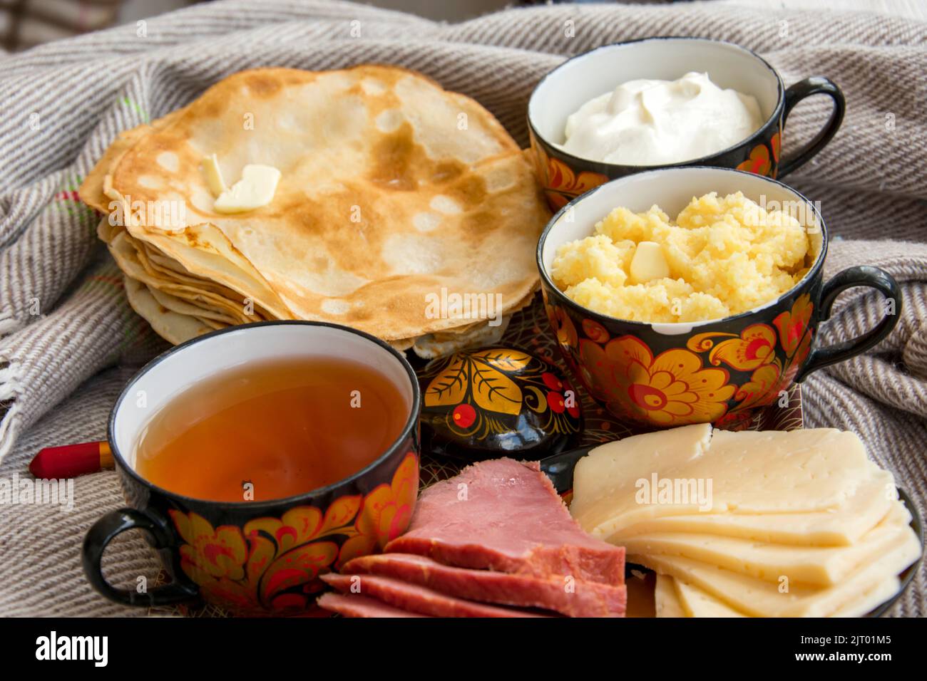 Colazione a letto per i tuoi cari, frittelle dolci con panna acida, formaggio e carne, corn porridge e una tazza di tè appena fatto. Buongiorno! Foto Stock