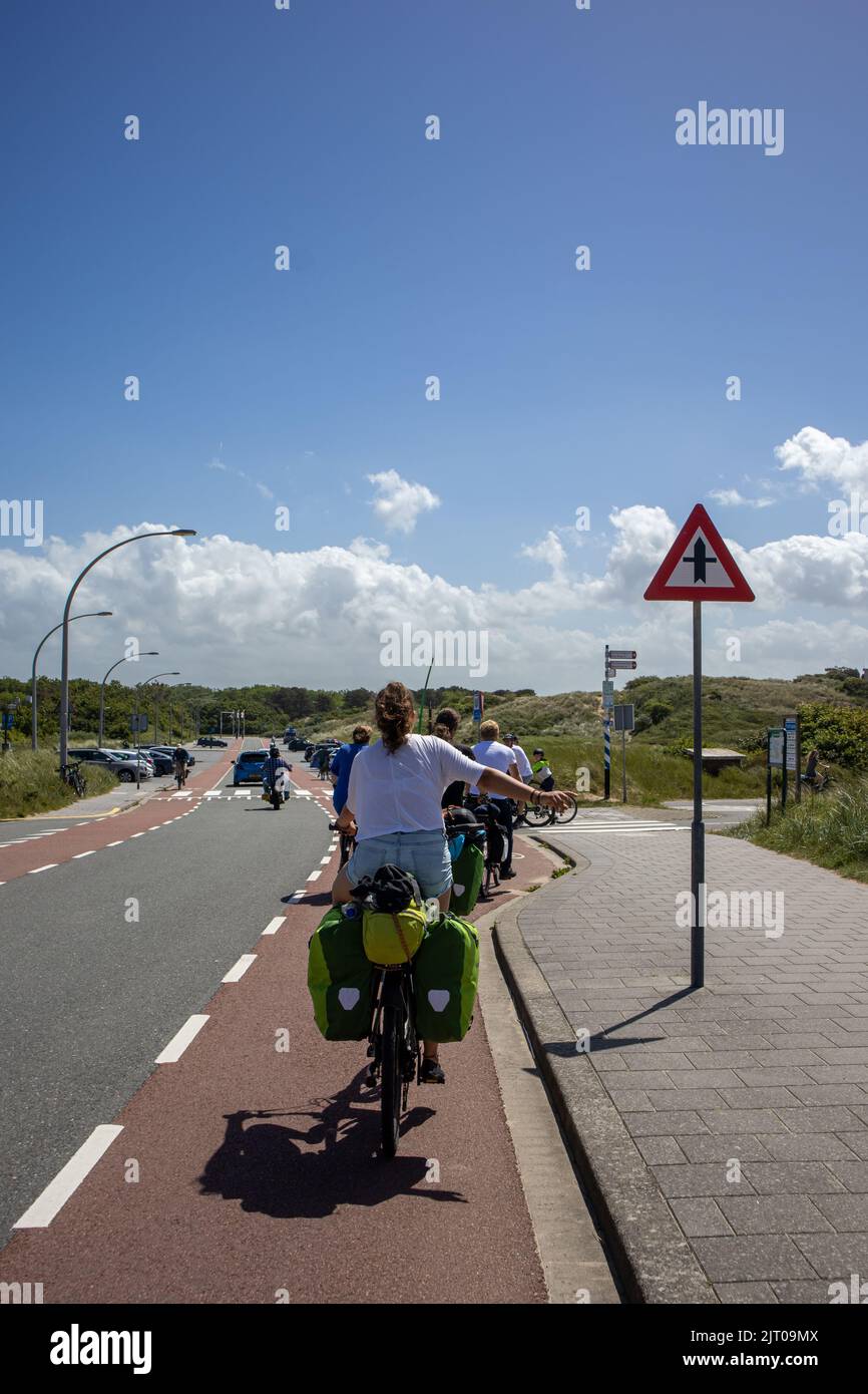 Un colpo verticale di un ciclista con le borse della bici che la attaccano la mano verso l'esterno il cielo blu sullo sfondo Foto Stock