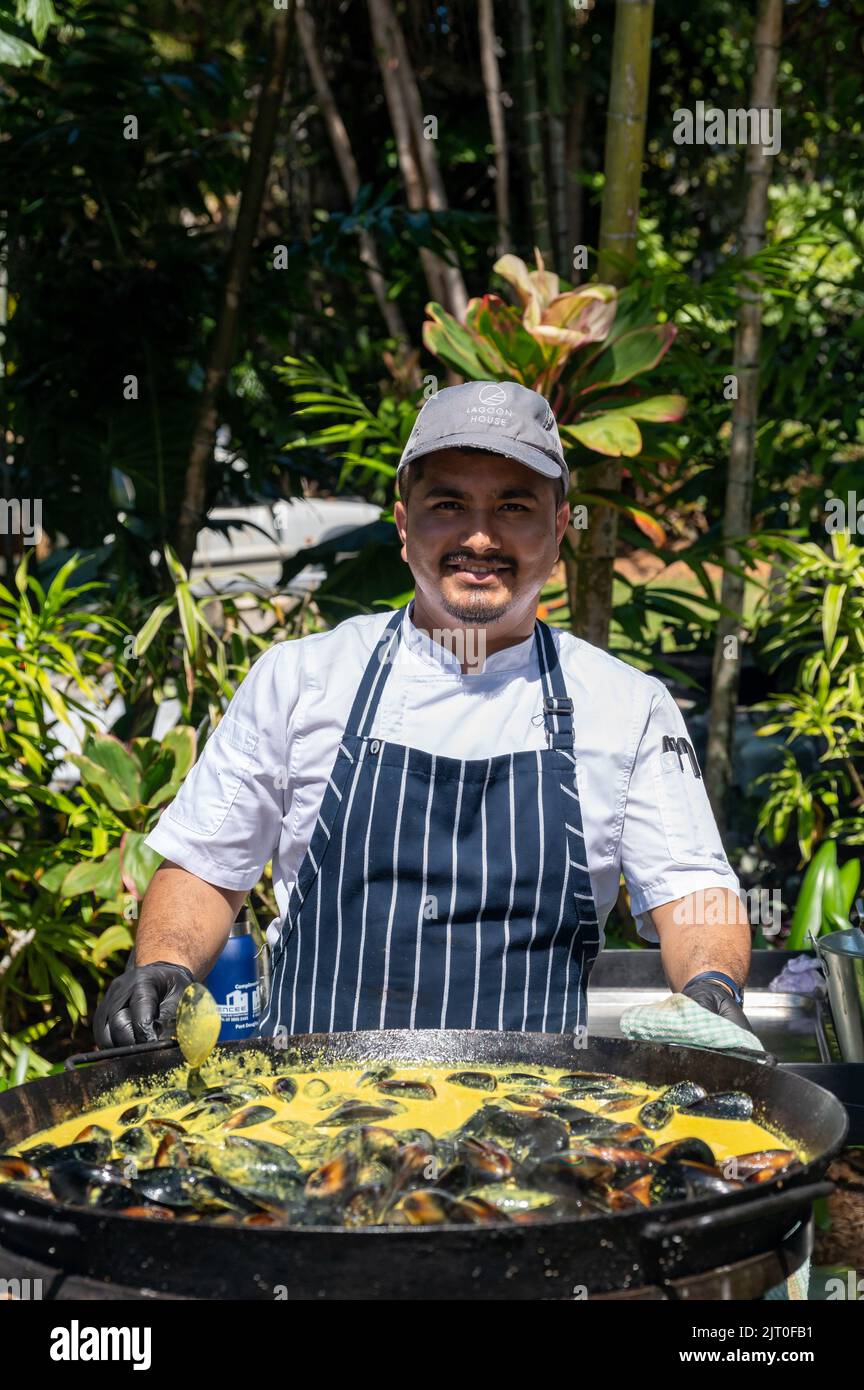 Chef all'esterno di fronte ad un grande wok che cucinano con orgoglio cozze al curry allo Sheraton Mirage Taste Port Douglas Food and drink festival Australia. Foto Stock