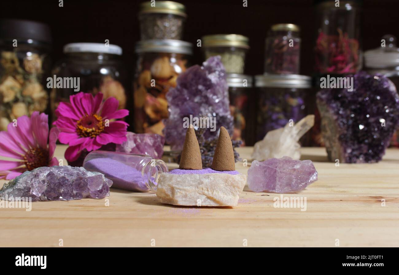 Cristalli di Ametista con fiori e coni di incenso sull'altare di meditazione Foto Stock