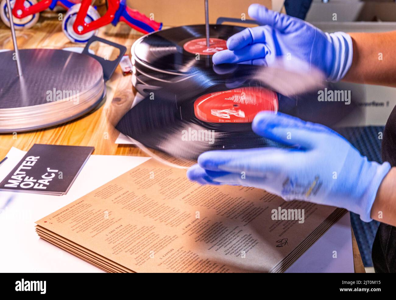 22 agosto 2022, Meclemburgo-Pomerania occidentale, Güstrow: I dipendenti della società discografica 'questione di fatto' controllano e imballano i record appena pressati nelle loro copertine. (L'azienda, che attualmente impiega cinque persone, produce record per diverse settimane in un ex locale per la patata, che ha dovuto essere ampiamente convertito per la produzione da record. Con una forza di 150 tonnellate, le lunghe registrazioni sono prodotte da cloruro di polivinile (PVC) sulle presse a 200 gradi Celsius. Ogni anno devono essere premuti tra 250.000 e 300.000 record. Secondo l'Associazione tedesca dell'industria musicale, Foto Stock