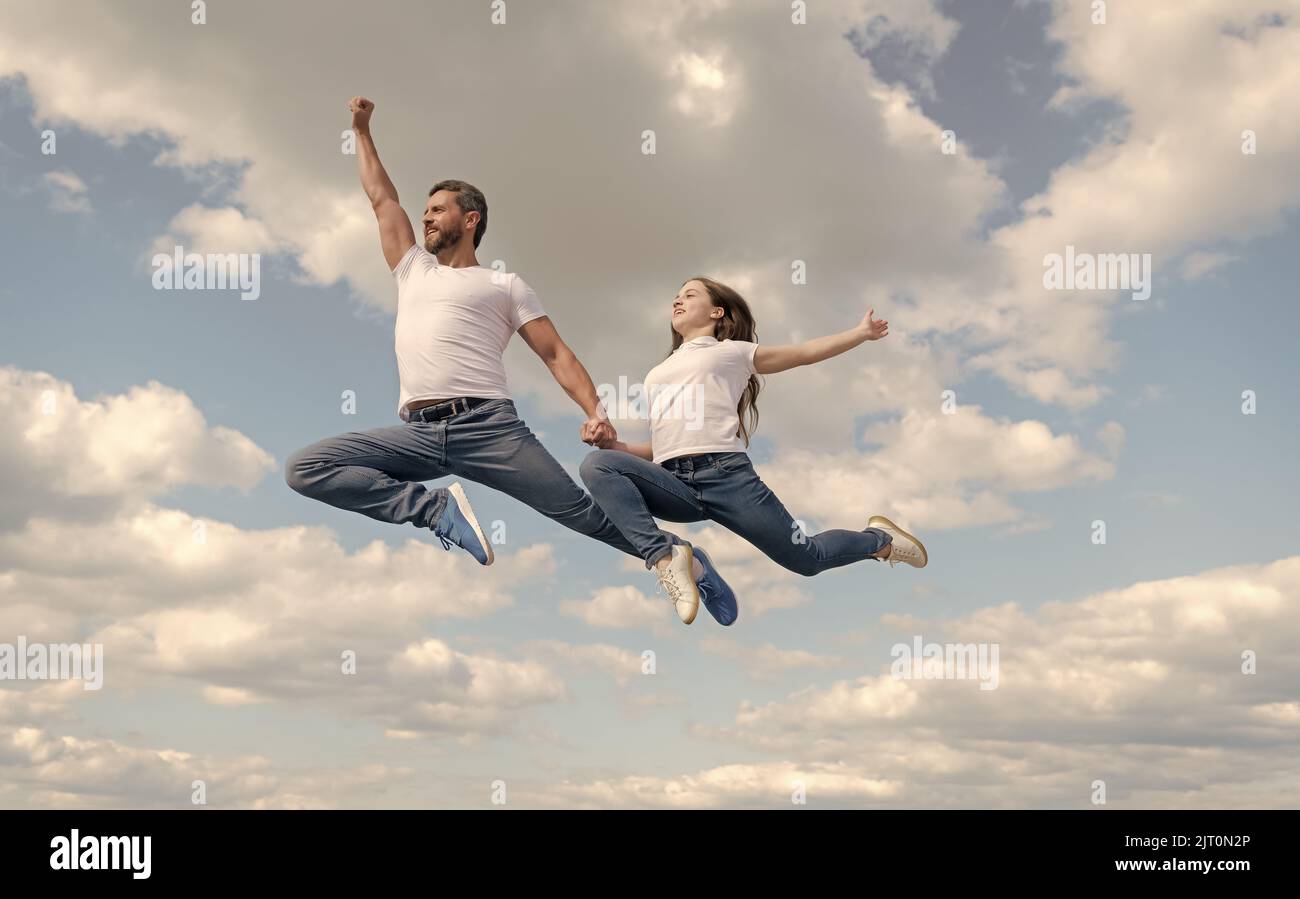 felice padre e figlia saltano in cielo. giorno di famiglia Foto Stock