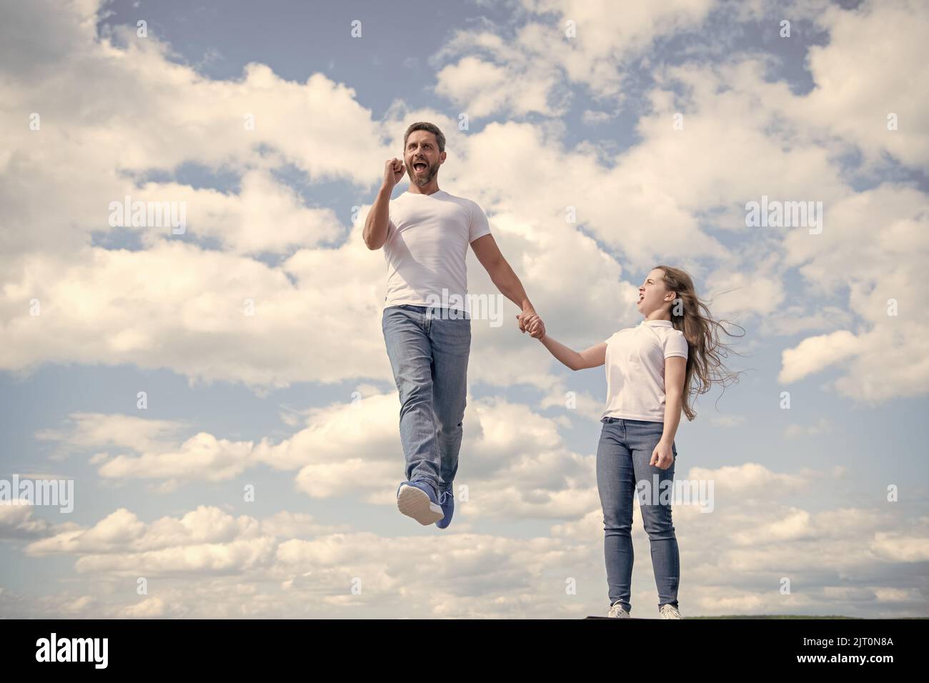 la figlia tiene suo padre ispirato che salta in cielo Foto Stock