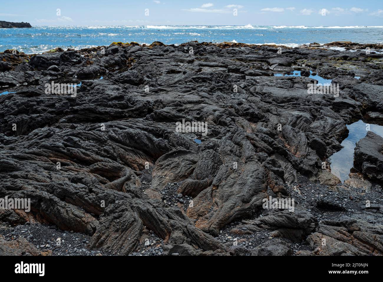 spiaggia rocciosa di sabbia nera punalu'u e oceano all'orizzonte lungo la costa kau delle hawaii sudorientali Foto Stock