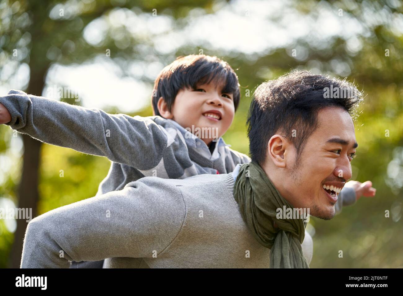 giovane padre asiatico che porta il figlio sulla schiena divertirsi godendo la natura all'aperto nel parco Foto Stock