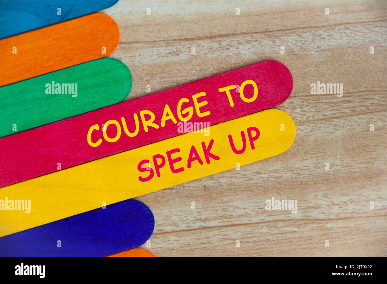 Coraggio di parlare in su testo su bastone di legno colorato - concetto di affari. Foto Stock