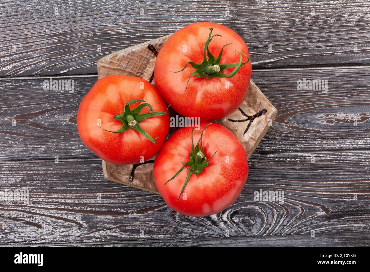 pomodoro su un piatto su sfondo di legno Foto Stock
