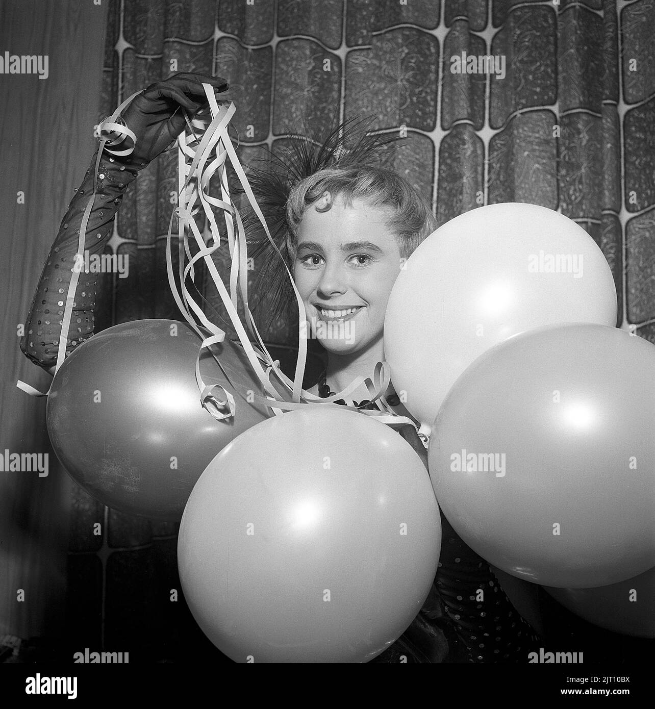 Festa negli anni '1950s. Una giovane donna tiene balloni e confetti e guarda la fotocamera sorridendo. Svezia 1955 Foto Stock