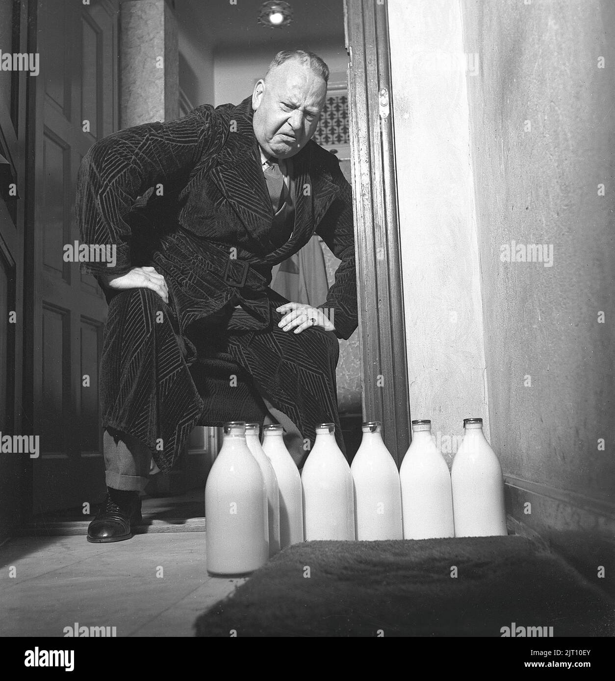 Uomo degli anni '1940s. Un uomo visibilmente deluso sopra le varie bottiglie di latte che si trovavano a casa sua. Ha soggiornato nell'appartamento della città mentre sua moglie e la sua famiglia hanno una vacanza estiva. Forse ha goduto della birra più del latte in questi giorni del bachelor. Svezia 1942 rif C22-4 Foto Stock