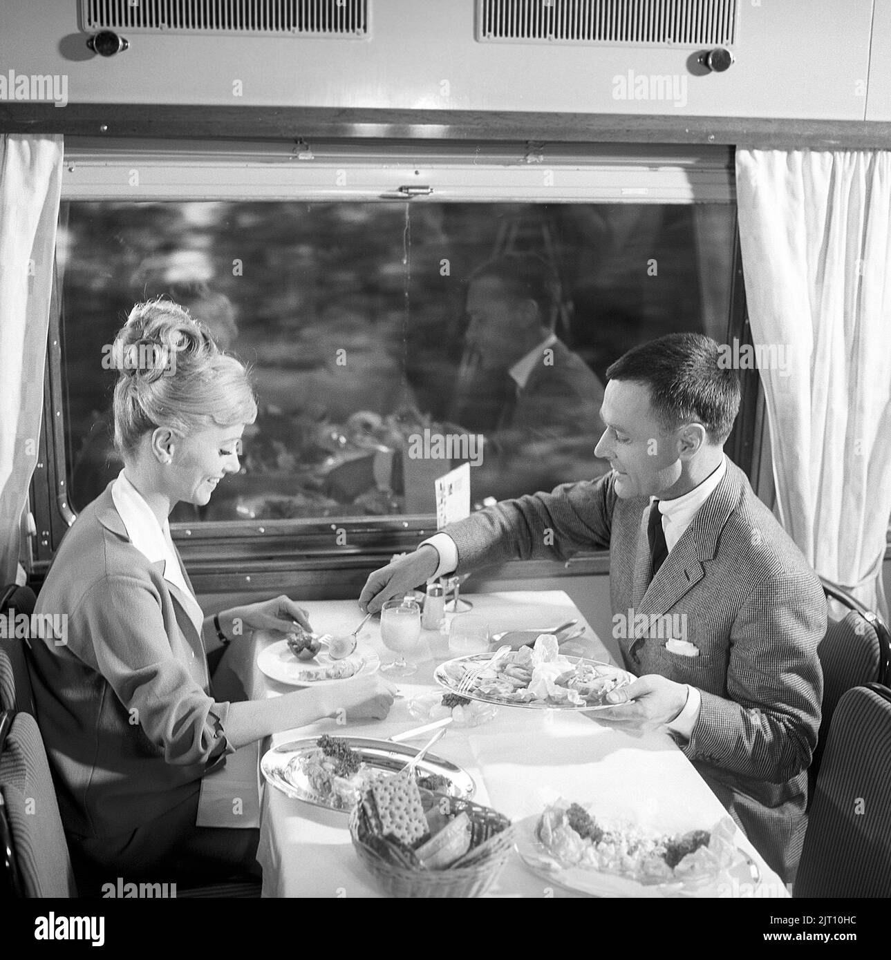 Viaggio in treno nel 1960s. Una coppia nella macchina del ristorante del treno sta godendo la cena insieme. Ha una tipica acconciatura 1960s. Svezia 1960s Kristoffersson Ref DD107-4 Foto Stock