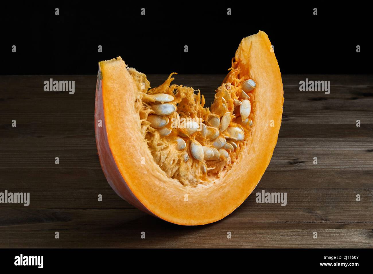 Fetta di zucca biologica fresca con semi su sfondo scuro Foto Stock