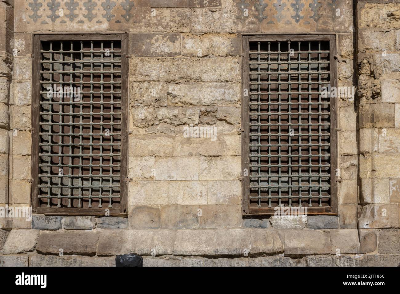 Vecchio muro di pietra danneggiato con telaio in legno e barre d'acciaio finestra Foto Stock