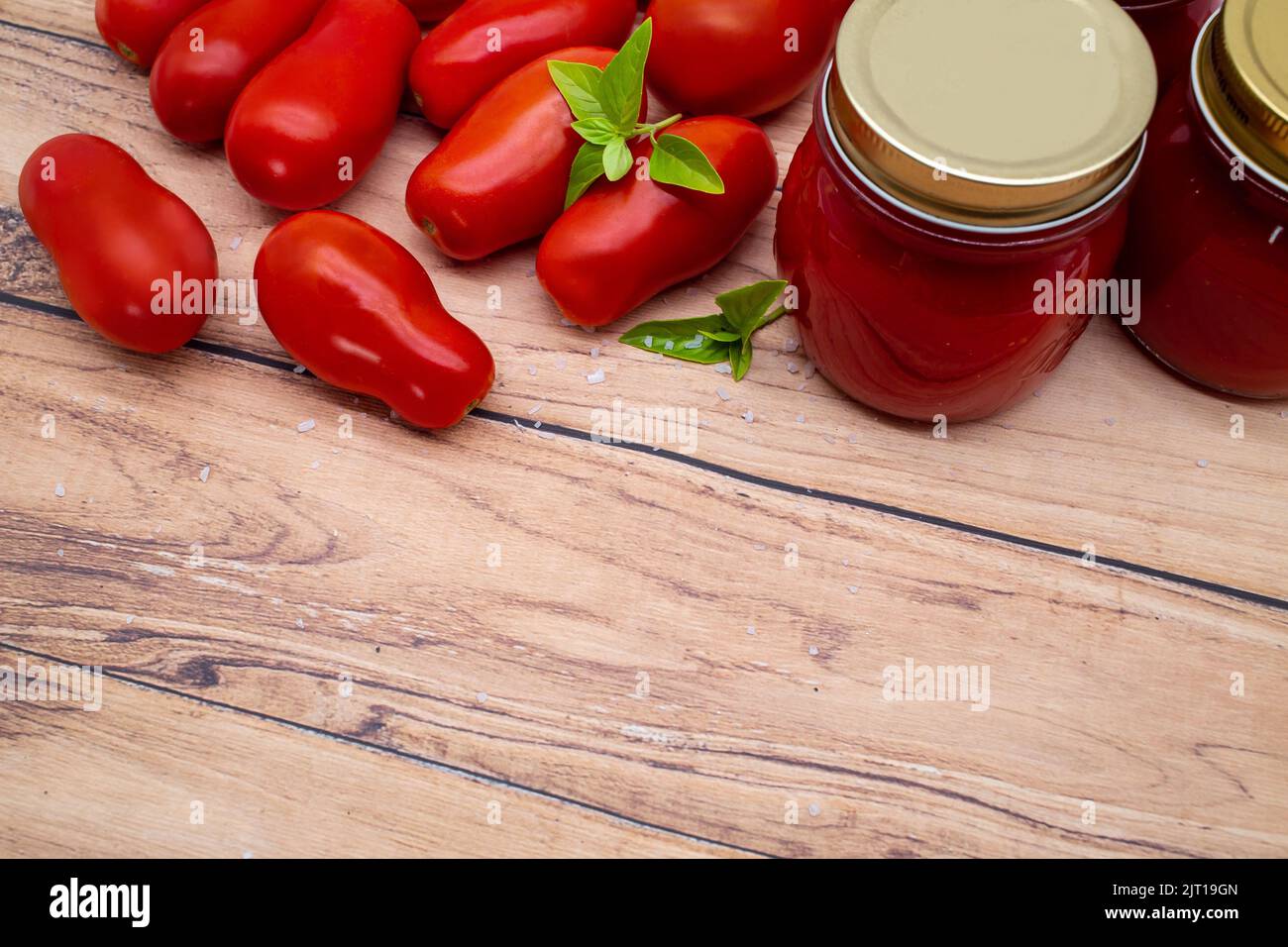 Tradizionale salsa di pomodoro italiana in un vasetto di vetro con pomodori freschi e basilico. Spazio di copia. Foto Stock
