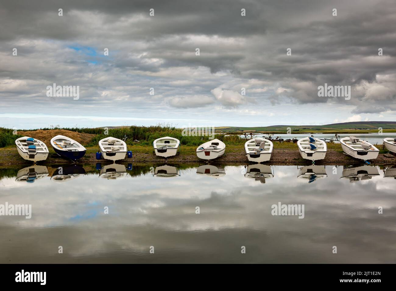 Loch Harray, Orkney, Regno Unito. 27th ago, 2022. I gommoni si riflettono nelle acque calme di Loch Harray, Orkney, Regno Unito. Le barche sono usate dagli appassionati locali di pesca a mosca. Credit: Peter Lopeman/Alamy Live News Foto Stock